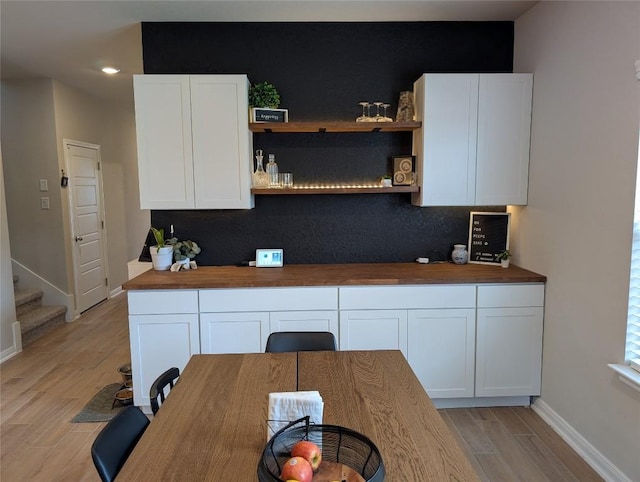 kitchen featuring white cabinetry, open shelves, butcher block counters, and light wood-type flooring