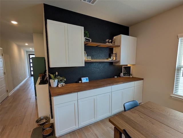 kitchen with white cabinets, light wood-type flooring, butcher block countertops, and open shelves