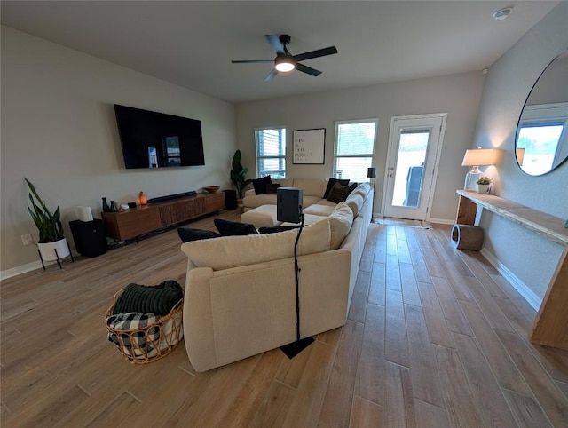 living area with ceiling fan, light wood-style flooring, and baseboards