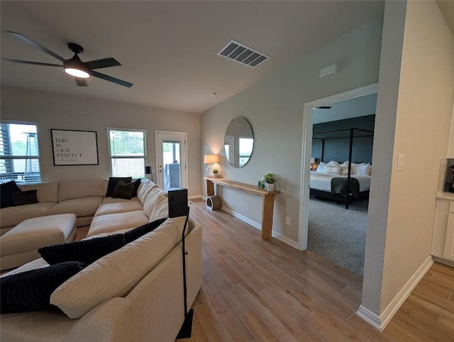 living room with baseboards, visible vents, a ceiling fan, and light wood-style floors