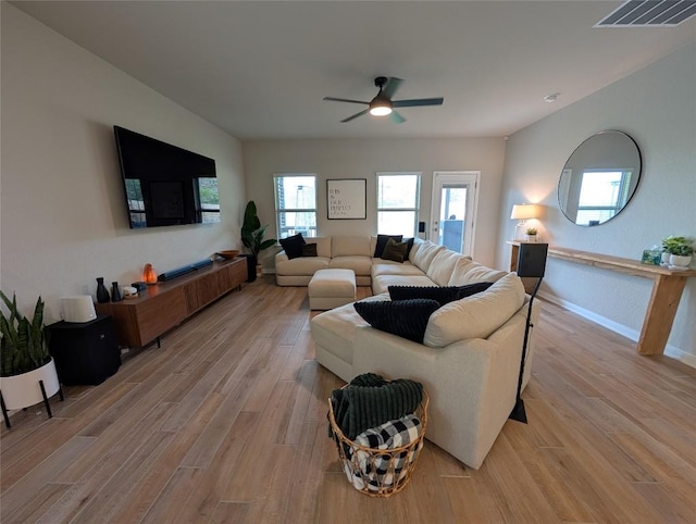 living room with light wood finished floors, visible vents, ceiling fan, and baseboards