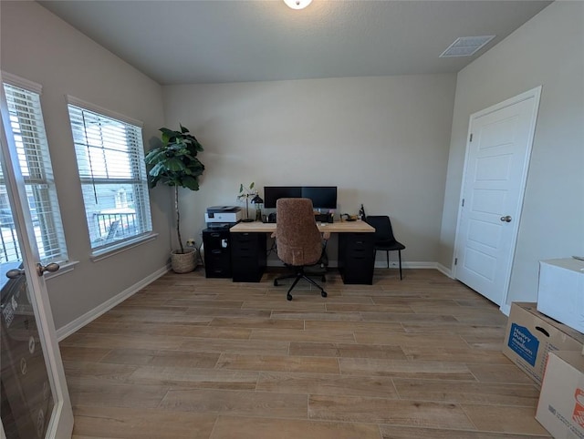 office space with visible vents, light wood-style flooring, and baseboards
