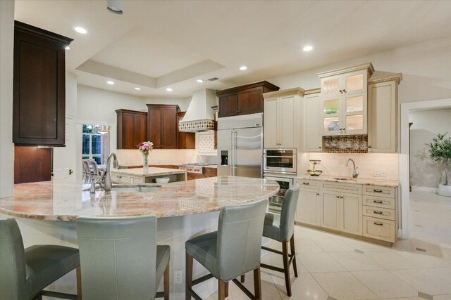 505 Newhall Cv, Austin, TX 78746 - kitchen with stainless steel appliances, a sink, custom range hood, light stone countertops, and recessed lighting