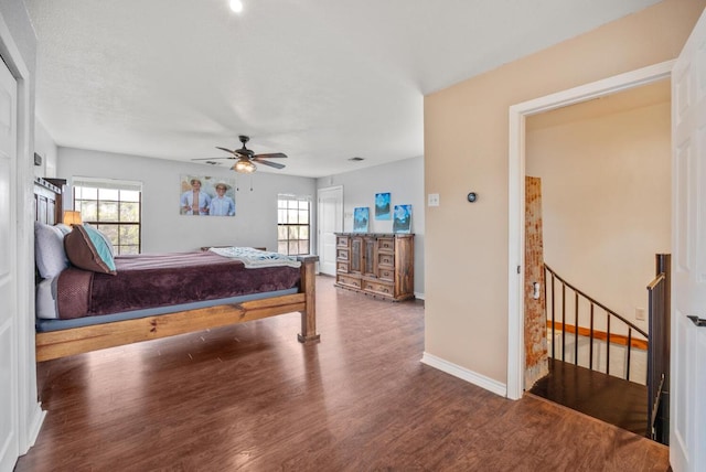 bedroom featuring baseboards, wood finished floors, a ceiling fan, and multiple windows