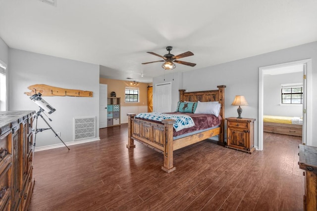 bedroom featuring baseboards, visible vents, wood finished floors, and multiple windows