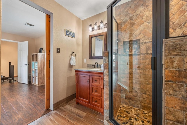bathroom with a shower stall, vanity, visible vents, a textured wall, and wood finished floors