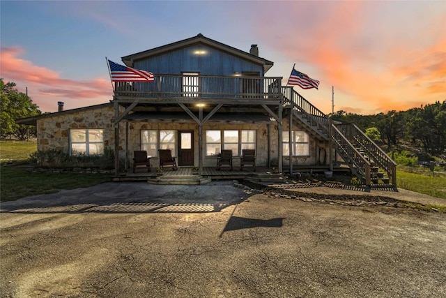 view of front of property featuring stairway, a deck, and stone siding