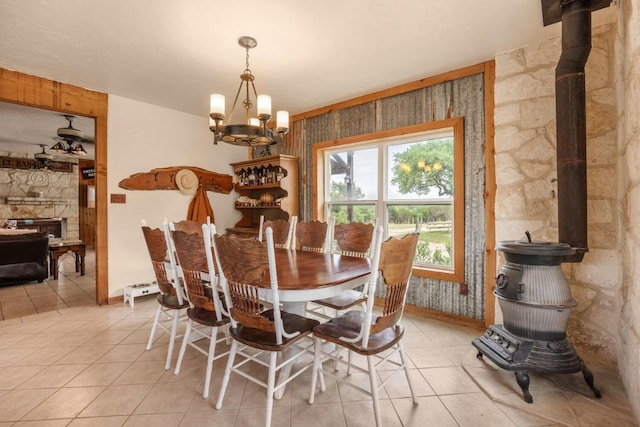 dining area with a chandelier, a wood stove, light tile patterned flooring, and baseboards