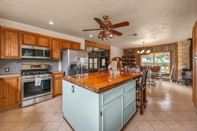 kitchen with light tile patterned floors, ceiling fan with notable chandelier, appliances with stainless steel finishes, and a sink