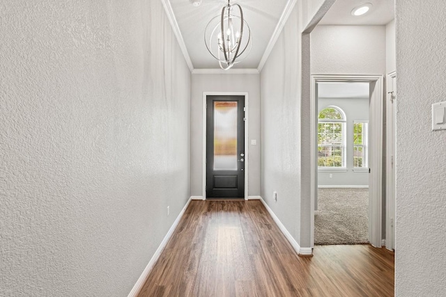doorway with an inviting chandelier, wood finished floors, a textured wall, and crown molding