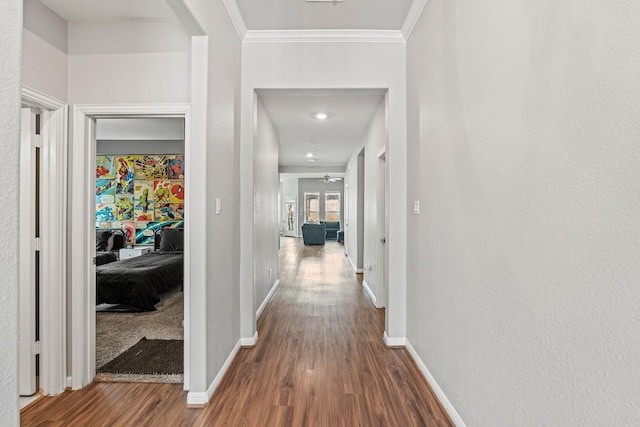 hallway with ornamental molding, wood finished floors, and baseboards