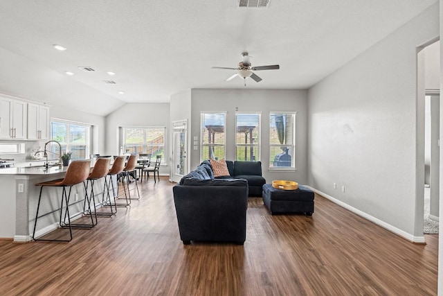 living room featuring vaulted ceiling, baseboards, visible vents, a ceiling fan, and dark wood-style floors