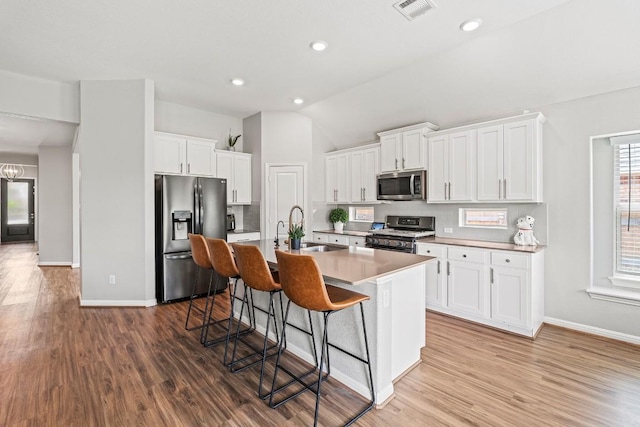 kitchen featuring visible vents, stainless steel appliances, wood finished floors, and a sink