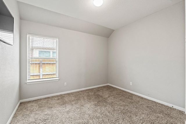 carpeted spare room with baseboards and lofted ceiling
