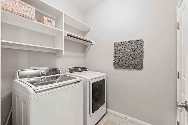 washroom with light tile patterned flooring, separate washer and dryer, laundry area, and baseboards