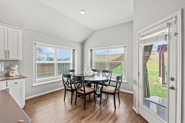 dining space featuring baseboards, a wealth of natural light, dark wood-style flooring, and lofted ceiling
