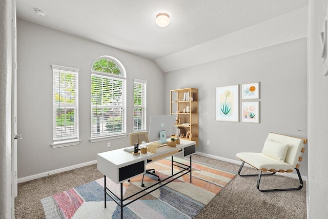office area featuring vaulted ceiling, light carpet, and baseboards