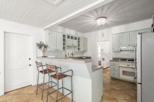 128 E Cedar St, La Grange, TX 78945 - kitchen with glass insert cabinets, freestanding refrigerator, light tile patterned floors, a kitchen bar, and a peninsula