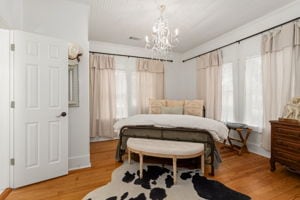 128 E Cedar St, La Grange, TX 78945 - bedroom with wood finished floors, a notable chandelier, and multiple windows