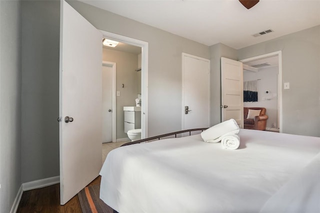 bedroom with wood finished floors, visible vents, connected bathroom, and baseboards