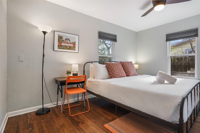 bedroom featuring wood finished floors, baseboards, a ceiling fan, and multiple windows