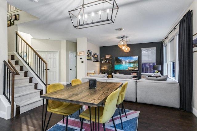 dining area with dark wood finished floors, stairway, visible vents, and baseboards