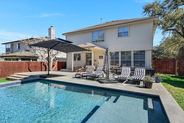 back of property featuring a fenced backyard, a fenced in pool, and a patio area