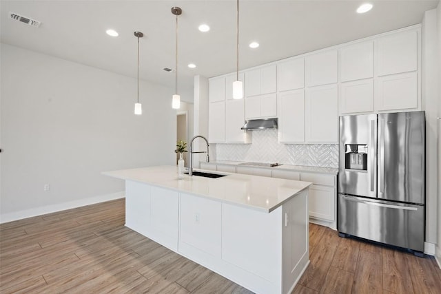 kitchen featuring light wood-style floors, stainless steel fridge with ice dispenser, backsplash, a sink, and visible vents