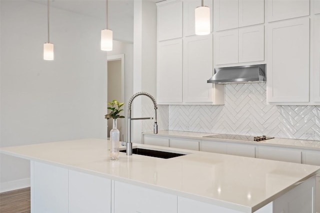 kitchen featuring a sink, black electric cooktop, backsplash, wall chimney range hood, and white cabinets