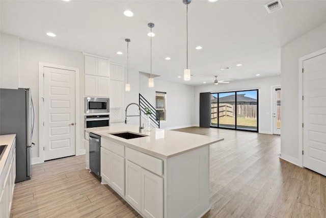 kitchen with a sink, light wood-type flooring, a ceiling fan, visible vents, and appliances with stainless steel finishes