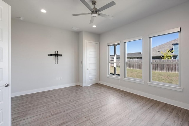 empty room with ceiling fan, recessed lighting, light wood finished floors, and baseboards