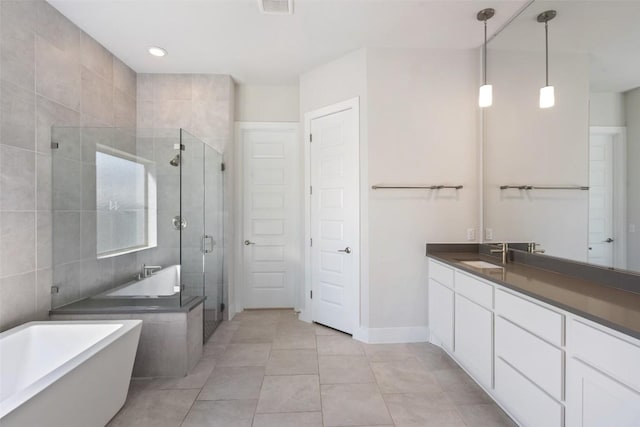 full bathroom featuring a shower stall, vanity, tile patterned floors, baseboards, and a soaking tub