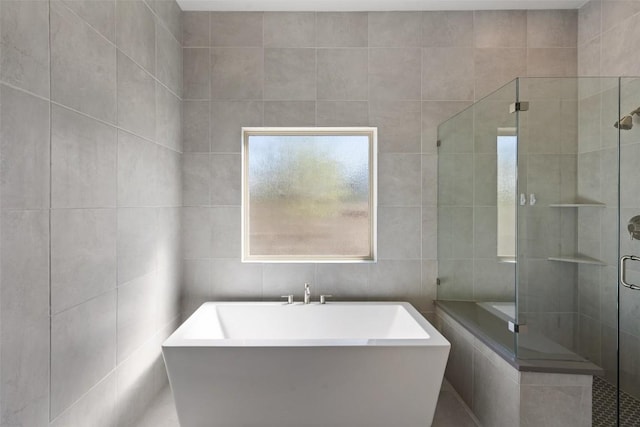 full bath with tile walls, a freestanding bath, and a shower stall
