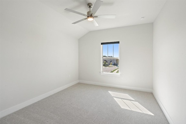 empty room with lofted ceiling, ceiling fan, carpet, and baseboards