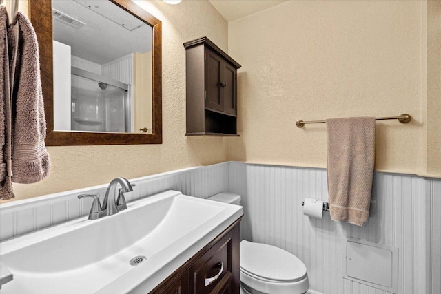 2605 Enfield Rd Unit 209, Austin, TX 78703 - full bath with toilet, a stall shower, a wainscoted wall, vanity, and a textured wall