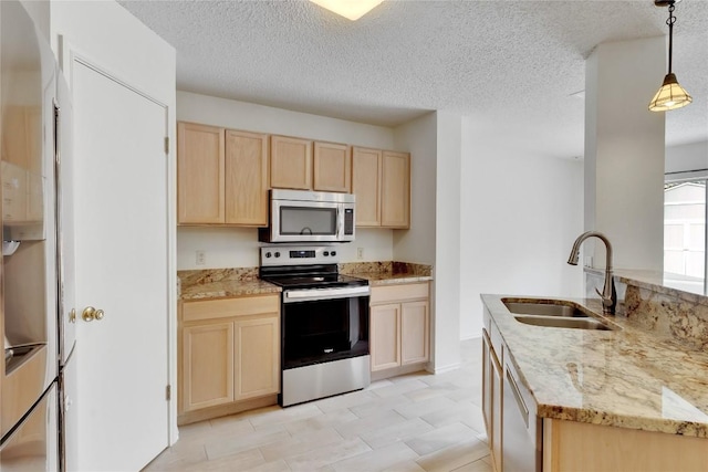 2009 Barnett Dr, Cedar Park, TX 78613 - kitchen with stainless steel appliances, light brown cabinetry, a sink, light stone counters, and hanging light fixtures
