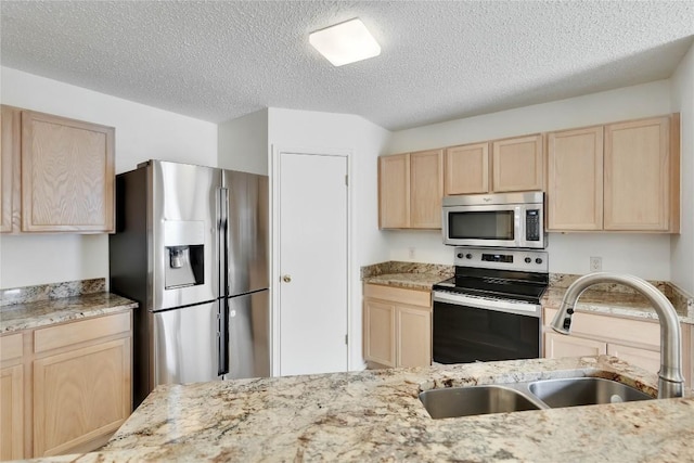 2009 Barnett Dr, Cedar Park, TX 78613 - kitchen with light brown cabinetry, stainless steel appliances, a textured ceiling, and light stone counters