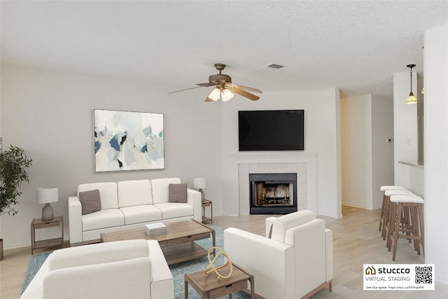 2009 Barnett Dr, Cedar Park, TX 78613 - living area featuring ceiling fan, a tiled fireplace, light wood-style floors, and baseboards