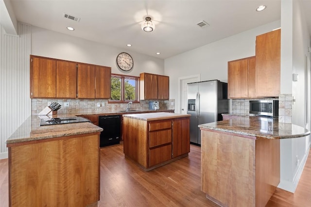kitchen with a sink, visible vents, appliances with stainless steel finishes, and brown cabinetry