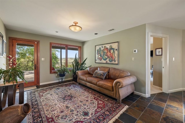 living room featuring visible vents, stone tile flooring, and baseboards