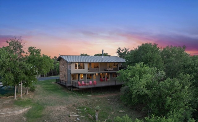 back of house with a deck, metal roof, a yard, and a standing seam roof
