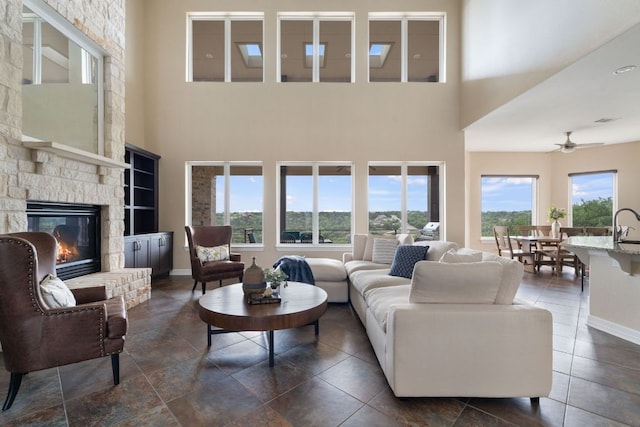 3207 Crystal Falls Pkwy, Leander, TX 78641 - living room with a stone fireplace, a ceiling fan, baseboards, and a wealth of natural light