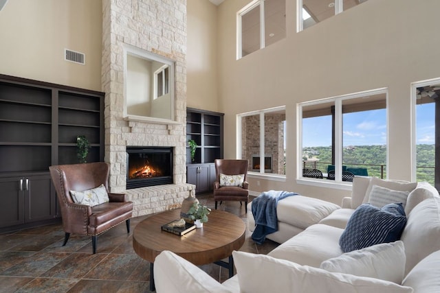 3207 Crystal Falls Pkwy, Leander, TX 78641 - living room with visible vents, a stone fireplace, a high ceiling, built in shelves, and stone finish flooring