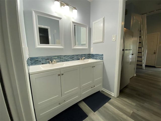 2815 Rio Grande St Unit 201, Austin, TX 78705 - bathroom featuring wood finished floors, double vanity, decorative backsplash, and a sink