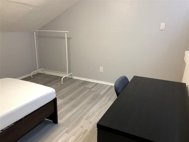 2815 Rio Grande St Unit 201, Austin, TX 78705 - bedroom with baseboards, light wood-type flooring, a textured ceiling, and vaulted ceiling