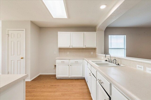 109 David Dr, Hutto, TX 78634 - kitchen featuring white cabinetry, decorative backsplash, a sink, light countertops, and light wood finished floors