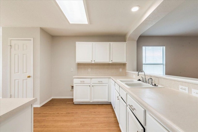 109 David Dr, Hutto, TX 78634 - kitchen with a sink, tasteful backsplash, white cabinetry, light wood-type flooring, and light countertops