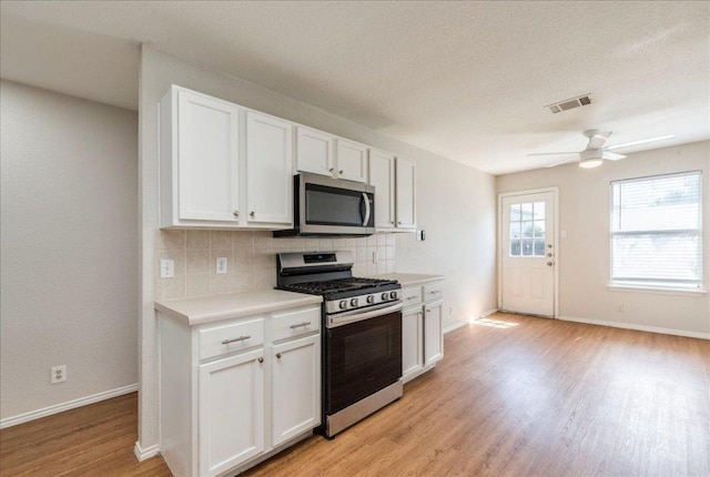 109 David Dr, Hutto, TX 78634 - kitchen featuring appliances with stainless steel finishes, light wood-style floors, decorative backsplash, light countertops, and white cabinets