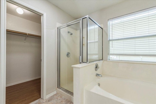 109 David Dr, Hutto, TX 78634 - bathroom featuring a bath, a stall shower, a walk in closet, baseboards, and wood finished floors