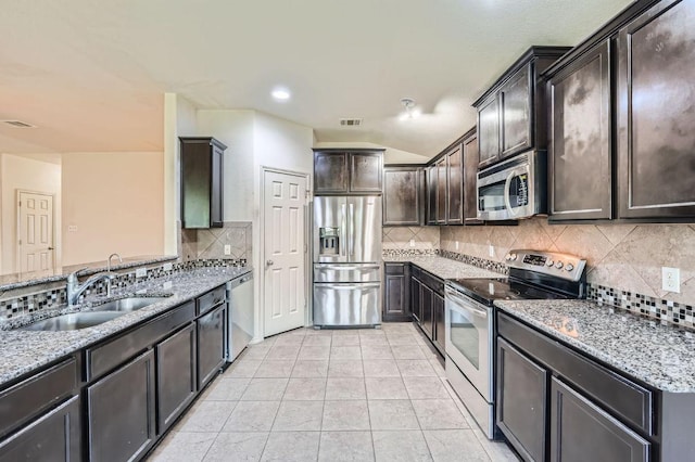 kitchen featuring light stone counters, a sink, appliances with stainless steel finishes, and tasteful backsplash